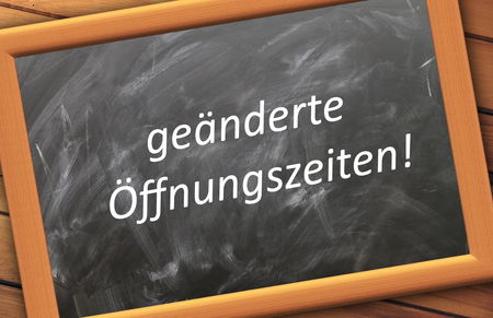 Schreibtafel mit Holzrahmen mit der Aufschrift "geänderte Öffnungszeiten!"